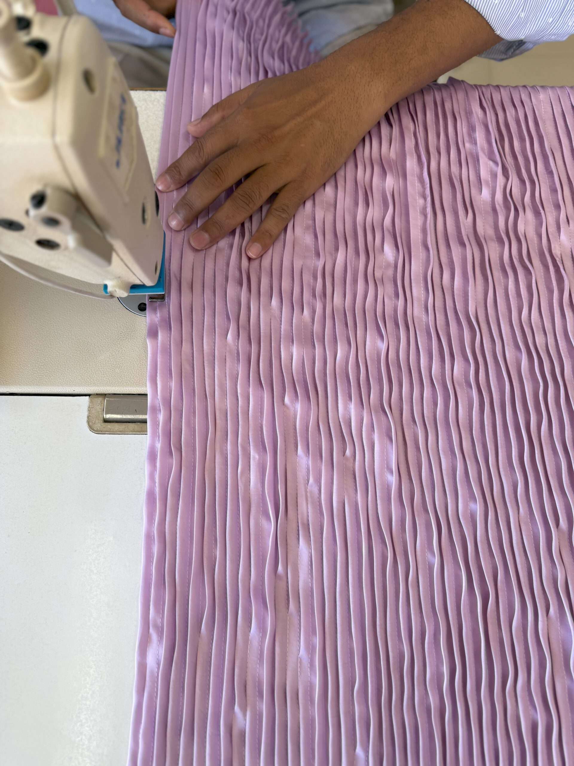 Arya Giri artisan sewing pleated lavender fabric with precision | Arya Giri's karighars