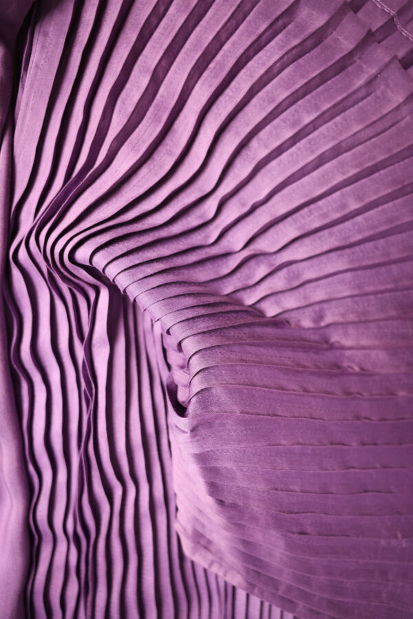 Close-up of pleated purple fabric – Arya Giri handwoven texture emphasizing rich drape and sheen.