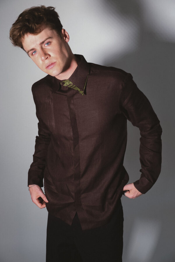 Man in dark brown linen shirt with green collar detail – Arya Giri menswear in handwoven linen showcasing timeless fabric craftsmanship.