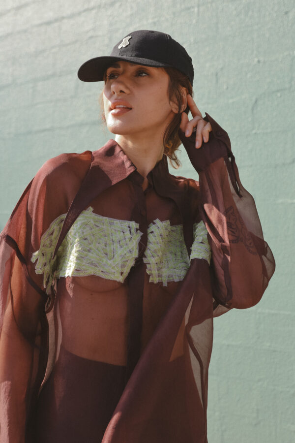 Woman wearing sheer brown organza shirt with embroidered green detail – Arya Giri womenswear highlighting handwoven organza styling.
